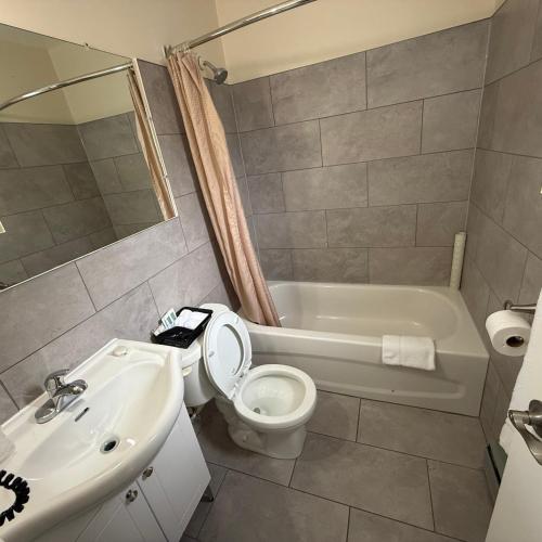 a bathroom with a toilet and a sink and a tub at Trunk Road Motel in Sault Ste. Marie