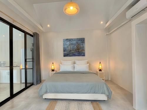 a bedroom with a large bed and two lamps on tables at The Arya Srithanu in Ko Kong Nui