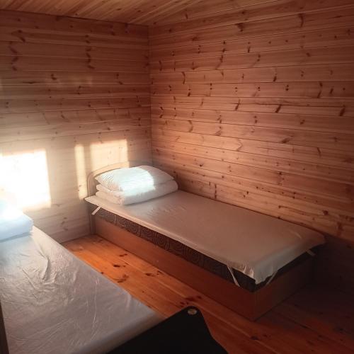 a room with two beds in a wooden walled room at Liepsna Šventoji in Šventoji