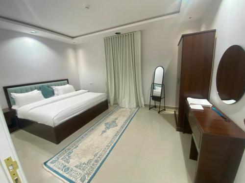 a bedroom with a bed and a desk and a chair at الكادي للشقق المخدومة in Ad Dawādimī