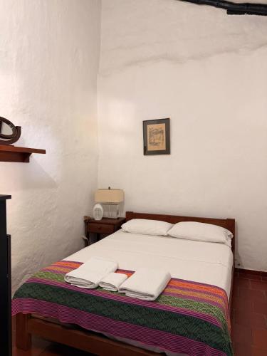 a bedroom with a bed with two towels on it at Casa Garaje in Barichara