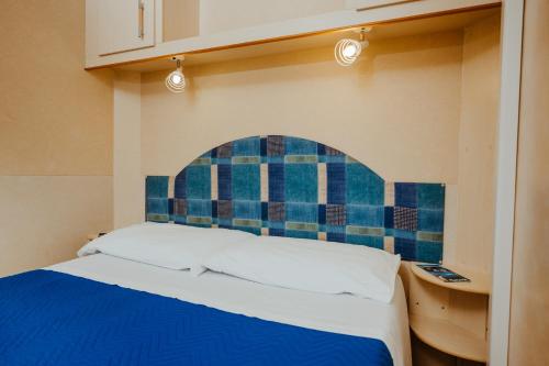 a bed in a room with a blue tiled wall at Green Garden Village con piscina, spiaggia riservata e parcheggio in Sirolo