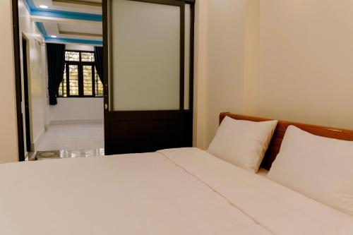 a bedroom with a bed with white sheets and a window at Ti Do Homestay in Ðức Hòa