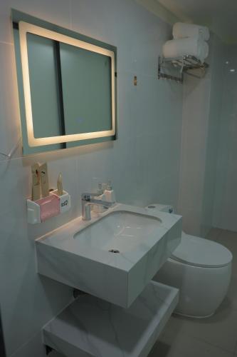 a white bathroom with a sink and a toilet at Ti Do Homestay in Ðức Hòa