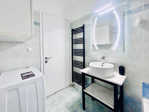 a white bathroom with a sink and a mirror at ITHACA Άνετο διαμέρισμα 3ου με θέα in Thessaloniki