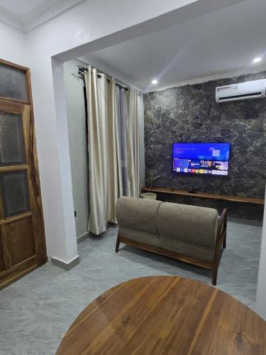 a living room with a couch and a tv on a wall at Verified Stone House in Dodoma
