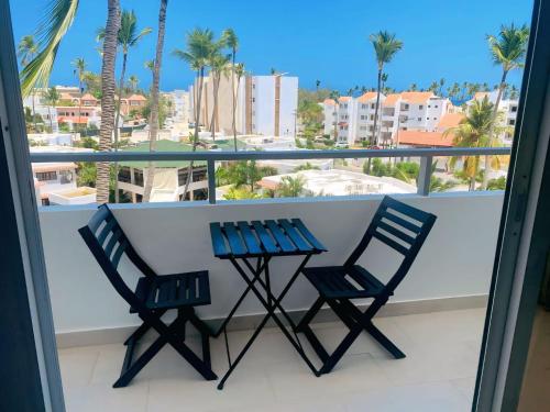 two chairs and a table on a balcony with palm trees at Hotel Beach Pool Punta Cana Vacation in Punta Cana