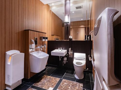 a bathroom with a sink and a toilet and a sink at APA Hotel Ginza Kyobashi Minami Tokyo Station Yaesu South Gate in Tokyo
