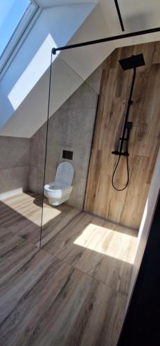 a bathroom with a toilet in a room with wooden floors at Dom Na Chwilę in Brzozowa
