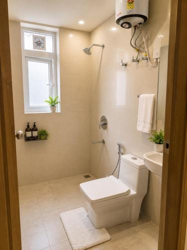 a bathroom with a toilet and a sink and a window at Halfway Home Cozy 2bhk in Rājpur