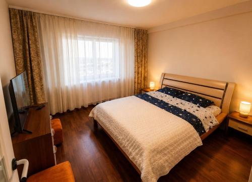 a bedroom with a bed and a large window at Central plaja Neversea in Constanţa