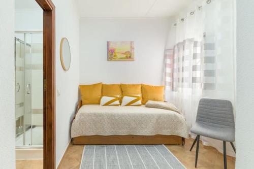 a bedroom with a bed with yellow pillows and a chair at Casa Lotus in Aljezur