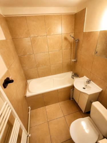 a bathroom with a tub and a toilet and a sink at Central plaja Neversea in Constanţa
