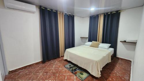 a small bedroom with a bed and blue curtains at Boca de Yuma Adventure in Yuma
