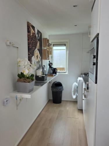 a kitchen with white walls and wooden floors at Robin's oak lodge in Epe