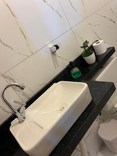 a white sink in a black counter in a bathroom at Chácara Marias Da Serra in Araruna