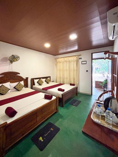 a hotel room with two beds and a window at Sigiri Nisala Resort in Sigiriya