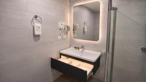 a bathroom with a sink and a shower with a mirror at Shitaye Suite Hotel in Addis Ababa