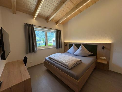 a bedroom with a bed and a table and a window at 6444 Apartment in Unterlängenfeld