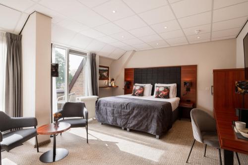 ein Schlafzimmer mit einem Bett und Stühlen in einem Zimmer in der Unterkunft Hotel De Oringer Marke Odoorn, nabij Emmen in Odoorn