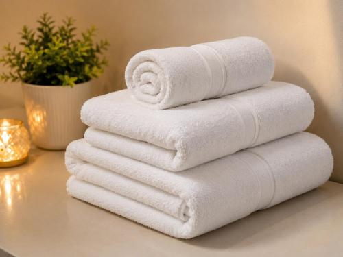 four towels stacked on top of each other on a table at The Azure Loft Nestory Stays in Rājpur
