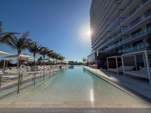 a swimming pool with palm trees and a building at Luxury View-Walk to beach! in Miami Beach