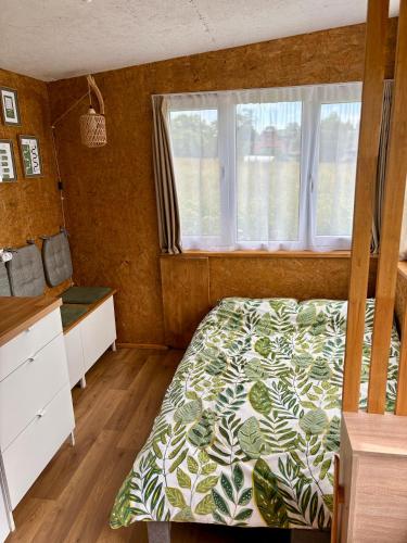 a bedroom with a bed and a window at Sajūtu dārza mājiņa in Augšlīgatne
