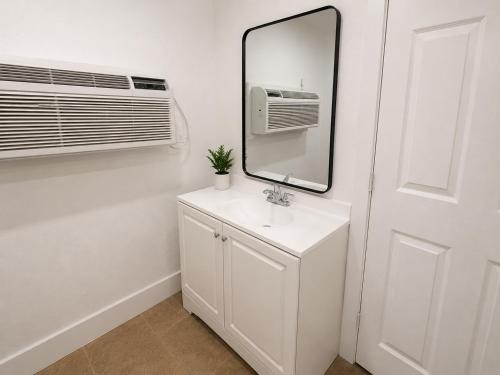 a bathroom with a sink and a mirror and a air conditioner at Sun Valley Motel in Phoenix