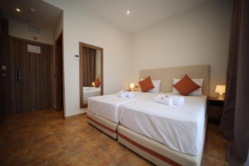 ein Schlafzimmer mit einem Bett mit weißen Laken und orangefarbenen Kissen in der Unterkunft Hotel El Karim in Oujda