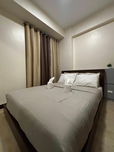 a bedroom with a large bed with two cups on it at 8 Newtown Mactan in Pajo