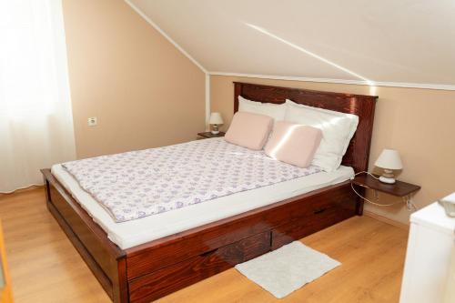 a bedroom with a wooden bed with two pink pillows at Golden BIS, Subotica in Subotica