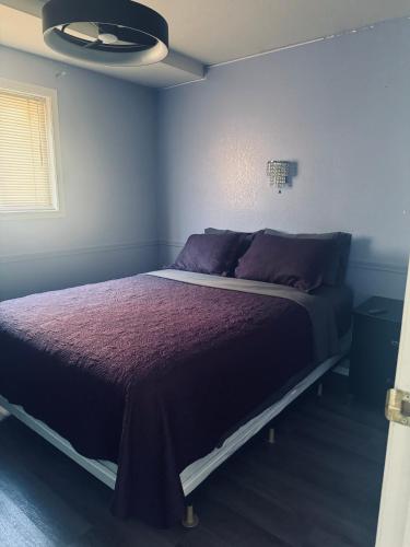 a bedroom with a large bed with purple sheets at Sunset Motel in Radium Hot Springs