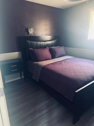 a bedroom with a bed with a purple comforter at Sunset Motel in Radium Hot Springs