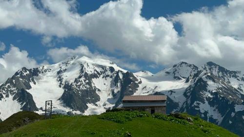 a snow covered mountain with a building on a hill at guesthouse twins in svaneti in Mestia