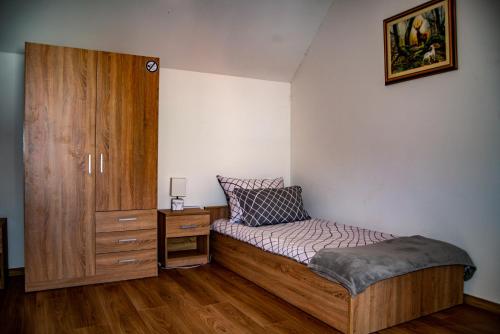 ein kleines Schlafzimmer mit einem Bett und einem Holzschrank in der Unterkunft Sobe HUBERTUS Lipovac Bajakovo in Lipovac