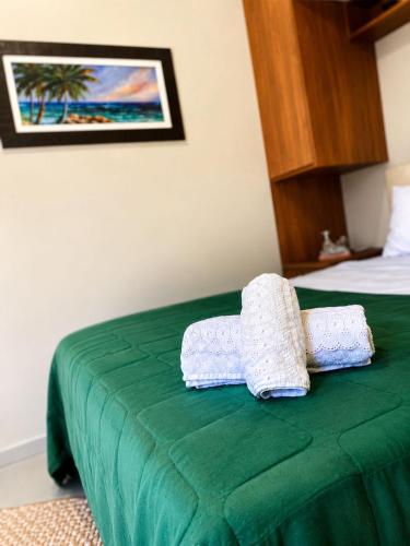 a green bed with two towels on top of it at Maria Lofts in Itaguaí