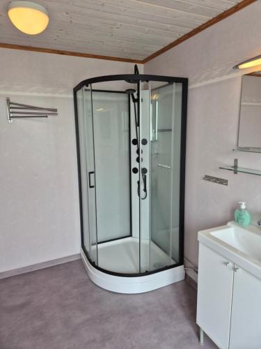 a glass shower in a bathroom with a sink at Klappa in Malmbäck