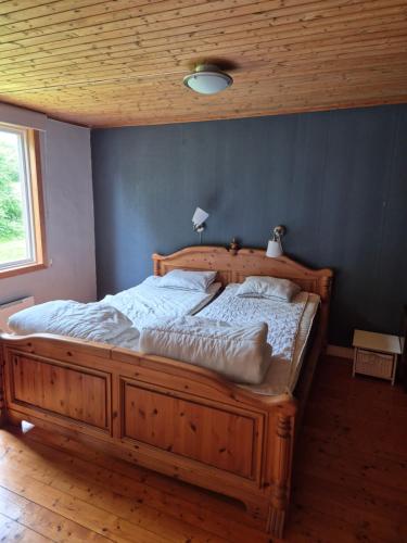 a large wooden bed in a bedroom with a blue wall at Klappa in Malmbäck