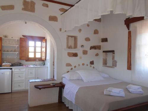 a white bedroom with a bed and a kitchen at PATMOS Mathios Studios- apartments in Patmos