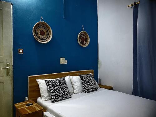 a bedroom with a blue wall and a bed with pillows at Au cœur de Ouidah in Ouidah