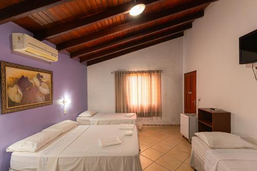 a room with two beds and a television in it at Pousada das Orquídeas in Pirenópolis