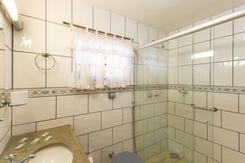 a white tiled bathroom with a sink and a shower at Pousada das Orquídeas in Pirenópolis