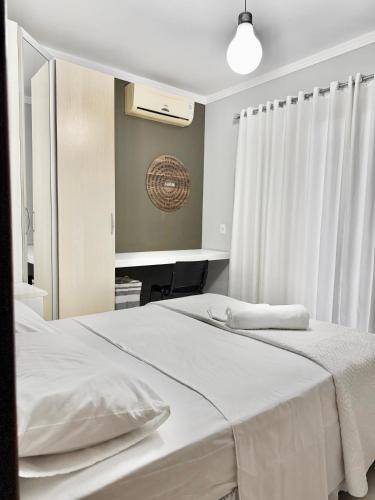 a bedroom with a large white bed and a mirror at Quarto 2P Joinville Costa e Silva perto Centro in Joinville