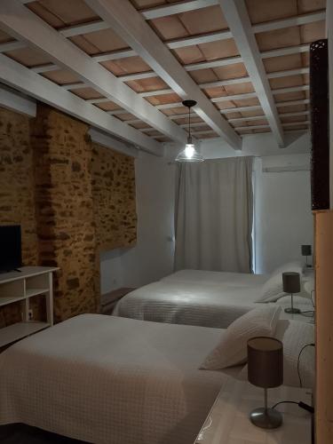 a bedroom with two beds and a tv and a brick wall at Convento Tarifa in Tarifa