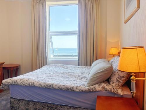 a bedroom with a bed and a window with the ocean at Downshire House in Douglas