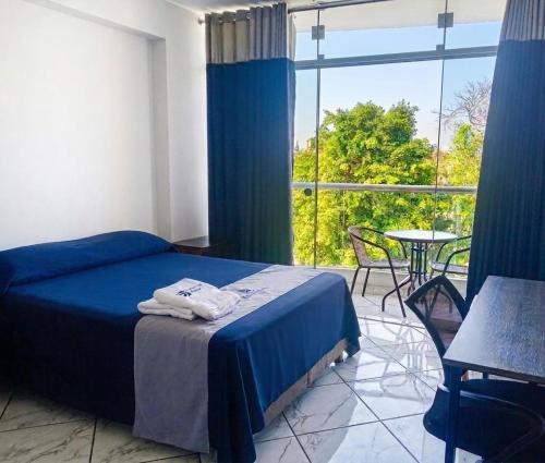 a bedroom with a bed and a table and a window at Regency Plaza Hotel in Pisco