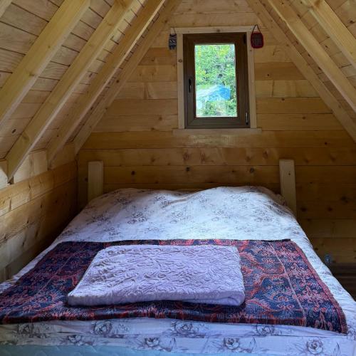 a bed in a log cabin with a window at Naš raj in Berane