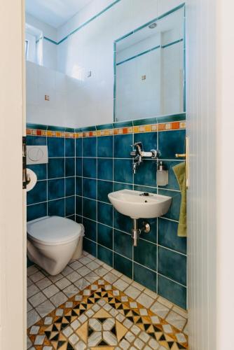 a blue tiled bathroom with a sink and a toilet at Villa Vista Pannonia in Donnerskirchen
