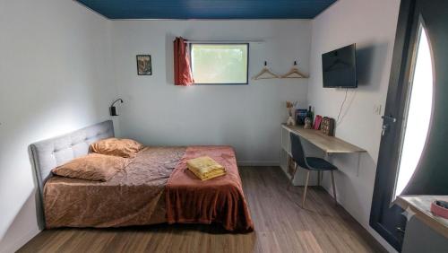a bedroom with a bed and a desk and a window at Entre Bois & Cévennes in Anduze