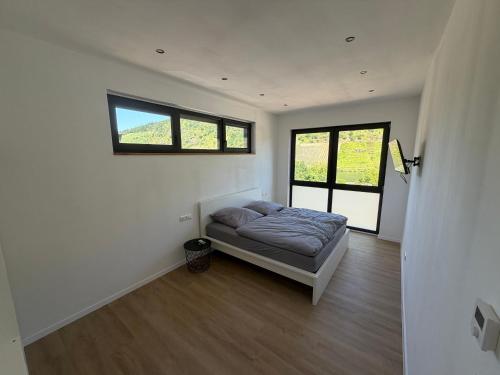 a bedroom with a bed in a room with two windows at Moselpanorama91 in Briedel